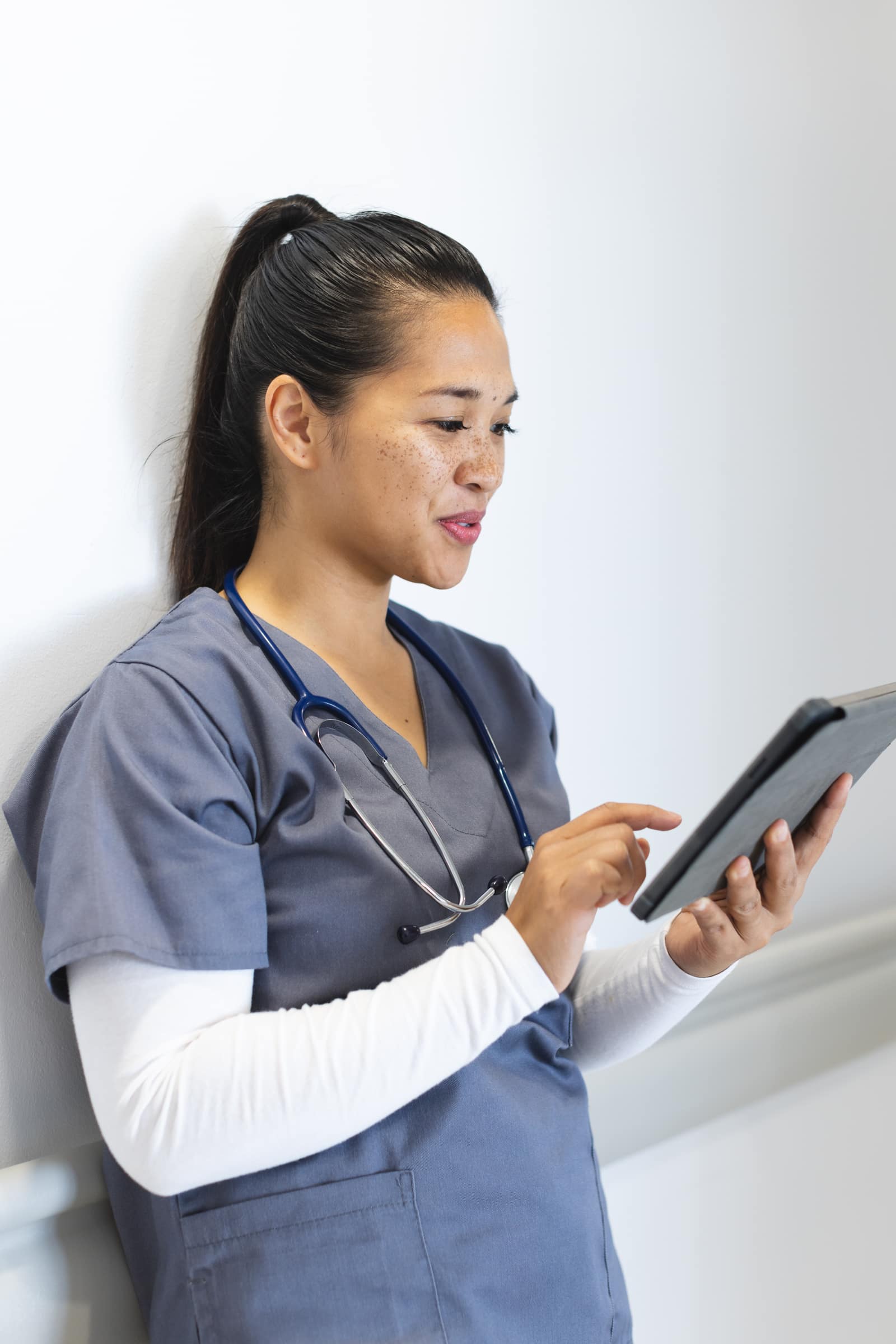 A physician reviewing credentials on a tablet in a hospital corridor